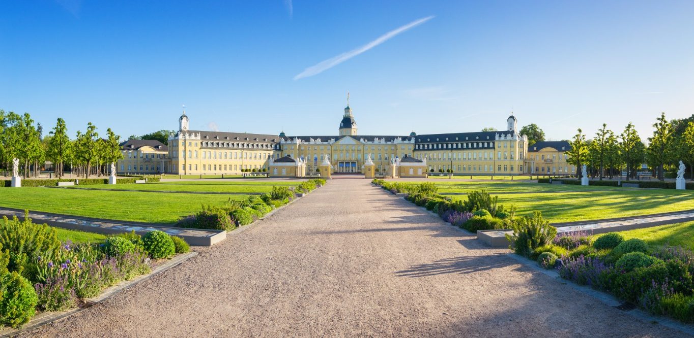 Eine weitläufige Gartenanlage mit einem historischen Gebäude im Hintergrund.