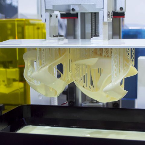 Industrieller SLA-3D-Drucker erstellt Prototypen aus Resin. Unternehmen können über 3D-Druck Lohnfertigung solche moderne Technologie flexibel nutzen, ohne in eigene Maschinen investieren zu müssen 3D-Drucker produziert eine komplexe, transparente Struktur aus einem flüssigen Material.