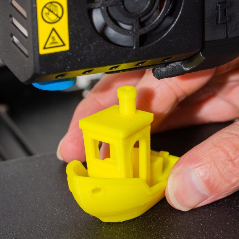 Gelbe 3D-gedruckte Bootsfigur wird von einer Person gehalten.