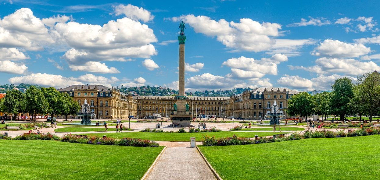 Panorama des Schlossplatzes mit historischen Gebäuden, Skulpturen und grünem Park.