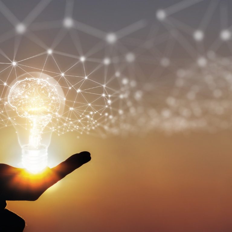 Eine Hand hält eine leuchtende Glühbirne, umgeben von einem Netzwerk aus Lichtpunkten.